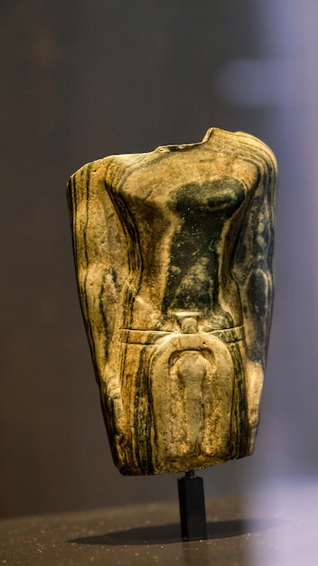 Sculpture of an Egyptian deity made of stone displayed in a museum