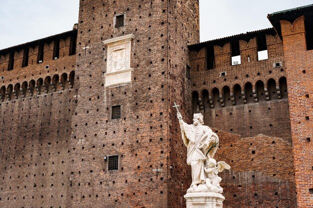 Sculpture of a man with a cross near the wall of castello sforzesco milan italy