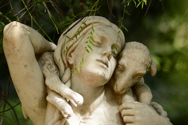 sculpture of a woman with a sheep or goat in her arms in the botanical garden of buenos aires in a natural green environment