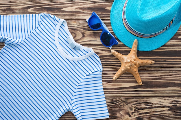 Sea background. Kid`s stuff on a wooden background. Flat still of child clothes.