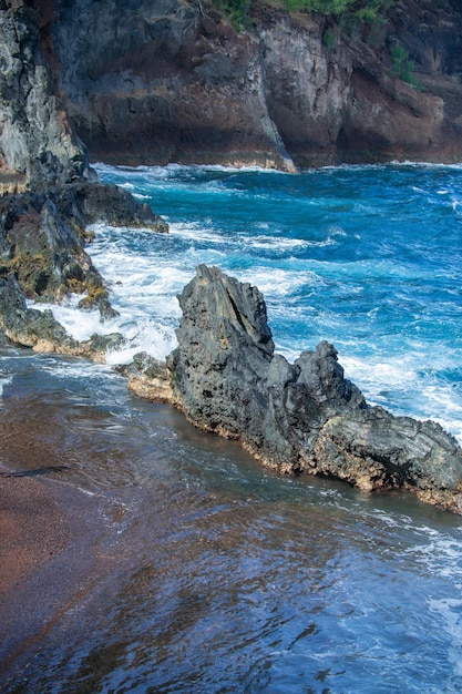 Sea background ocean wave crashing on rock coast with spray and foam before storm