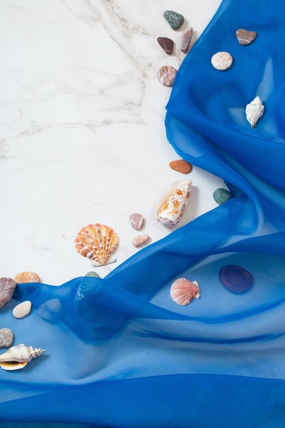 Sea background with blue cloth stones seashells on white marble