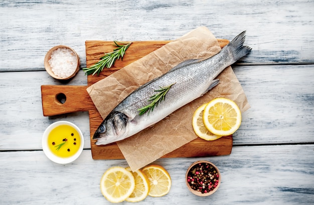 sea bass  fish with lemon  and spices on wood background