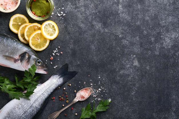 シーバス生新鮮な海の魚のバス、塩コショウパセリオリーブオイルとレモン、ダークコンクリートの素朴な背景調理する準備ができている新鮮な魚料理の背景上面図コピースペース