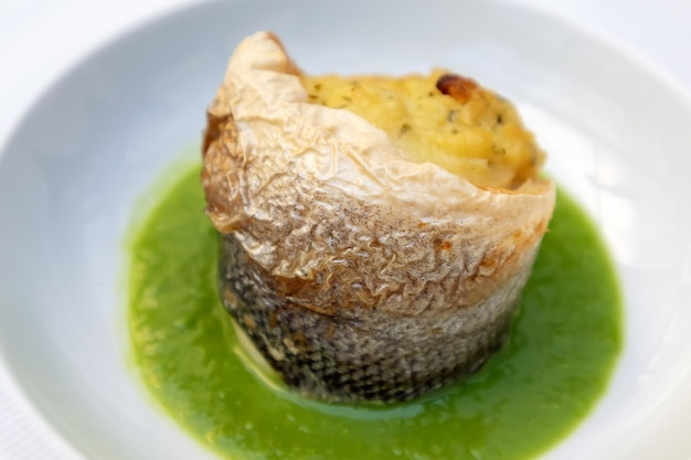 Sea bass with pea sauce served in a white plate italian restaurant menu