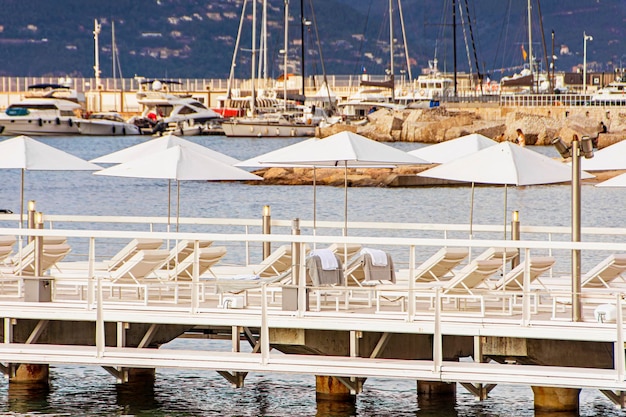 Sea bay and pier with yachts boats and beach umbrella in Cannes