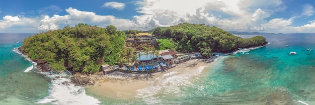 Sea bay with turquoise water and a small white beach Beautiful lagoon and volcanic island covered with dense forest view from above