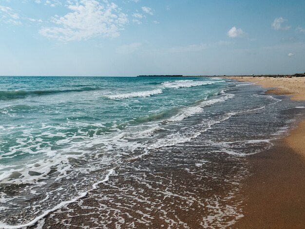 海の青いアクアマリンの波が日当たりの良い砂浜に並んでいます。海の泡の柔らかい波。