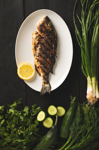 Sea bream on a white plate with green vegetables