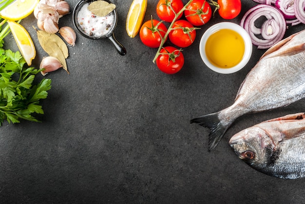 Sea bream with ingredients for cooking on black stone table