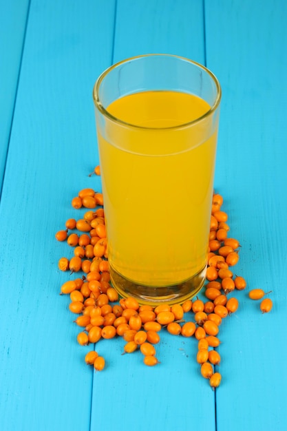 Photo sea buckthorn juice in a glass beaker on wooden background closeup