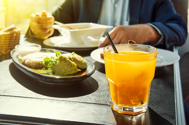 Sea buckthorn juice in yellow glass on a wooden table as part of a business lunch