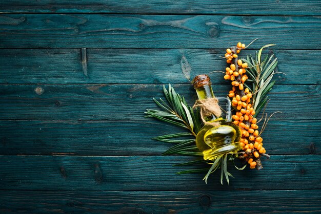 Sea buckthorn oil. Fresh sea buckthorn berries on a twig. Top view. Free space for your text.