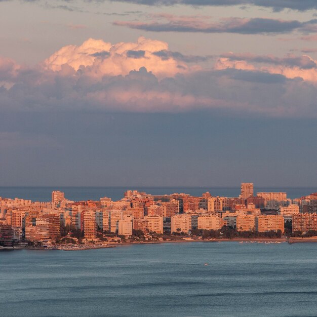 Sea and buildings against sky at sunset