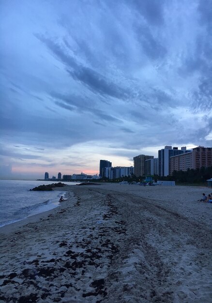 Sea and buildings against sky at sunset