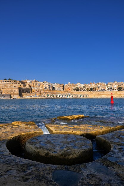 Sea by buildings against clear blue sky