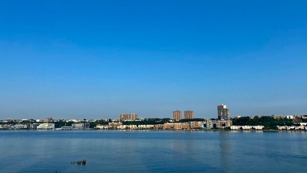 Sea by buildings against clear blue sky