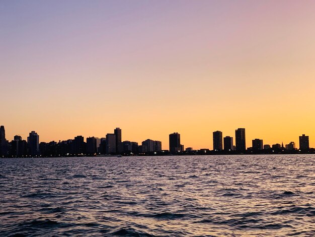 Photo sea by buildings against clear sky during sunset