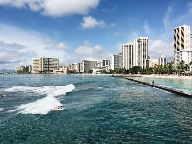 Photo sea by buildings against sky in city