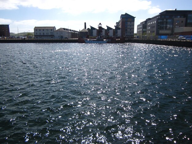 Sea by buildings against sky in city