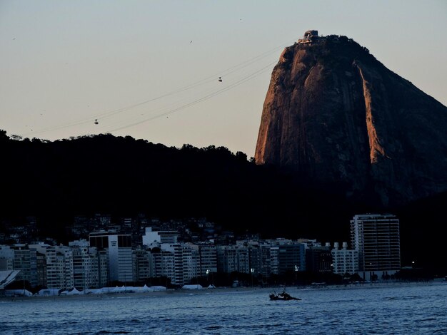 写真 夕暮れの晴れた空に照らされた海と都市