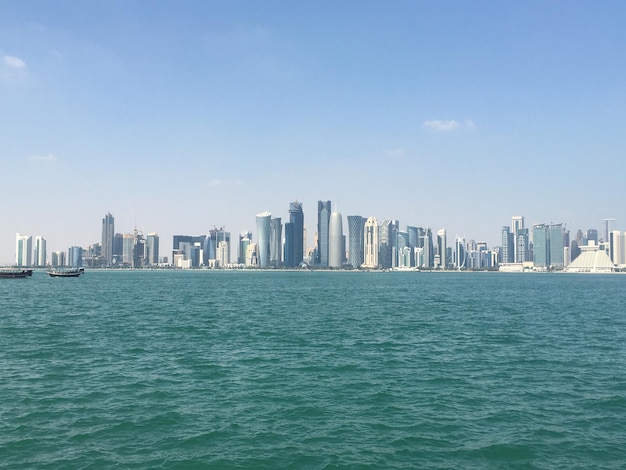 Photo sea by modern buildings against sky in city