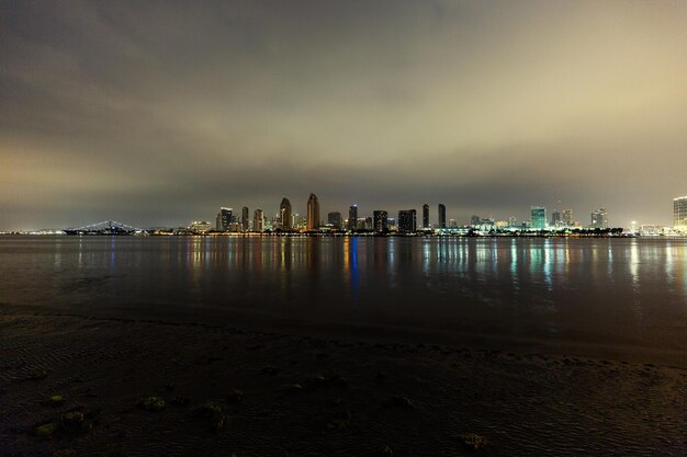 Photo sea by modern buildings against sky at night