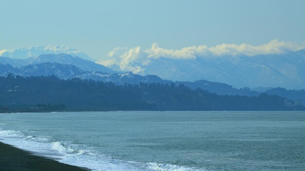 Sea by snow covered mountains against clear sky on sunny day near the city kobuleti adjara georgia