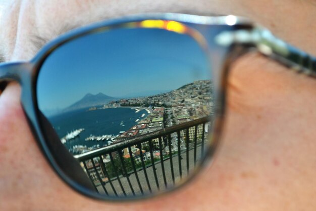 Foto mare e paesaggio cittadino riflessi su occhiali da sole