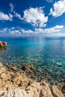 Costa del mare con acqua turchese chiaro e pietre taglienti sul capo cavo greco, cipro. telaio verticale.