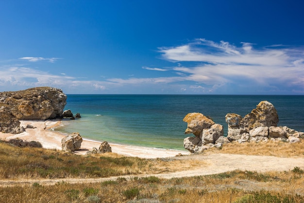 Sea coast with sandy beach and day with rocks on clear day