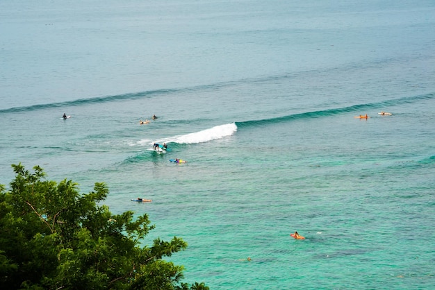 Sea coast with waves on Bali island and people surfing