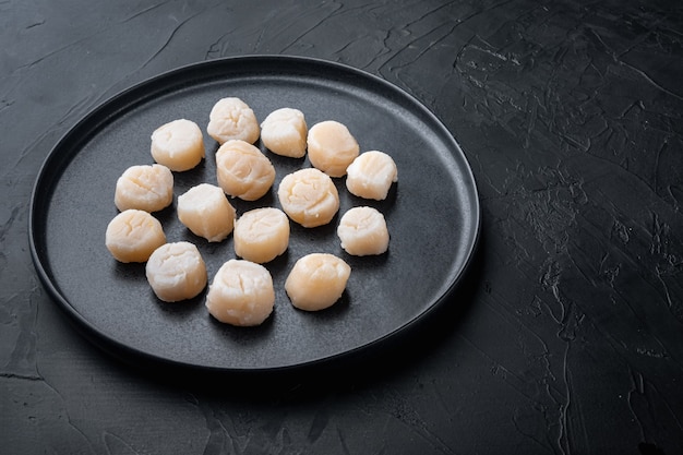 Sea delicacies, raw scallops, on black table