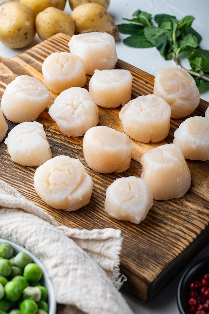 Sea delicacies, scallops with potato, green pea and mint, on white textured background