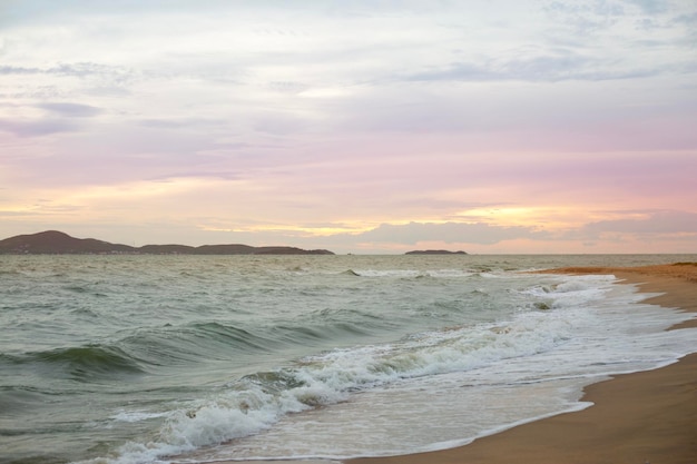 Sea foam wave crashes on the sunset sand beach