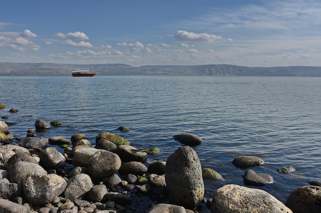 Sea of Galilee surrounded by rocks under the sunlight and a blue cloudy sky in Israel