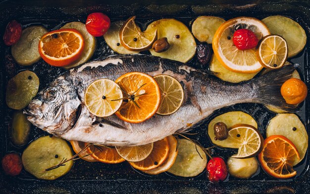 Sea gilthead bream fish on the plate baked with tasty selection of tropical fruits and vegetables