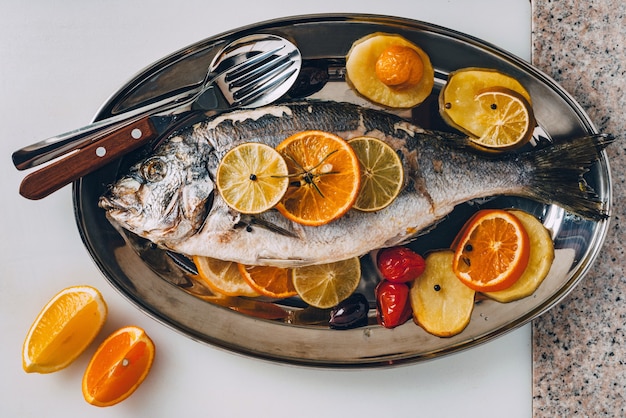 Sea gilthead bream fish on the plate baked with tasty selection of tropical fruits and vegetables