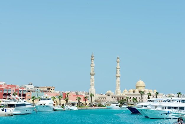 Sea harbour with stone city embankment with parked speed boats and Hurghada Mosque