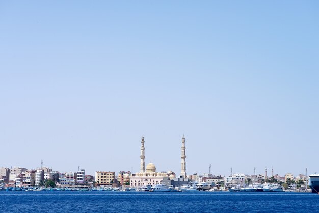 Sea harbour with stone city embankment with parked speed boats and Hurghada Mosque