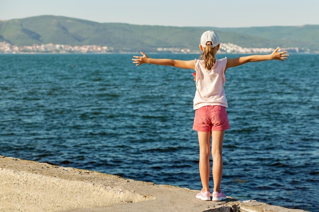 Sea Holiday Happy Teen girl Enjoying Sea on pier with hands out Back view Summer vacation