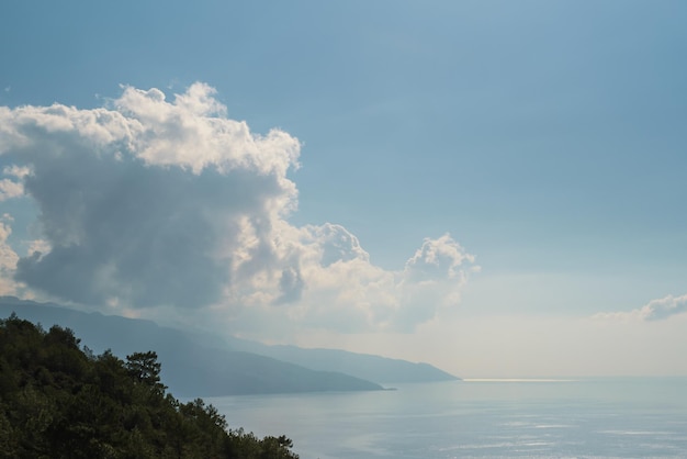 Sea and mountains view with white fluffy clouds scenic panoramic shot at noon on the Aegean coast idea for background or wallpaper