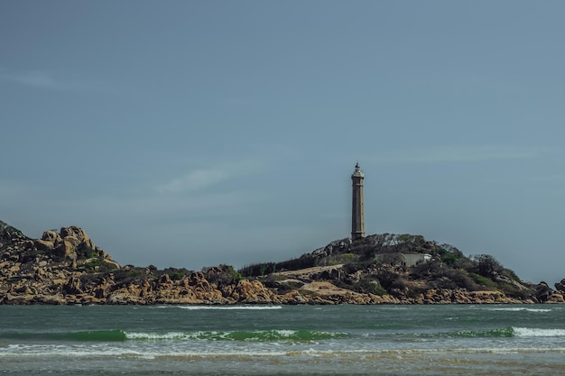 Sea nature panoramic view landscape background Ocean rocky cliffs forested island Clear blue sky Lighthouse on mountain top Signal warn sailors shipwreck travel concept hope purpose of life