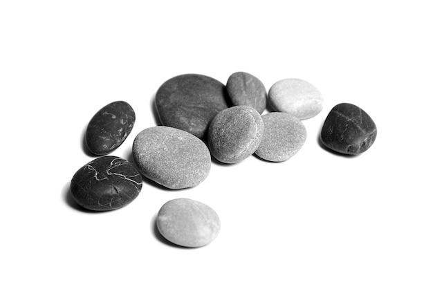 Морская галька Куча гладких серых и черных камней на белом фоне