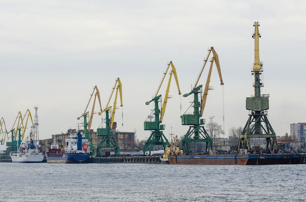 Sea port with cranes, ships at the pier for loading goods.