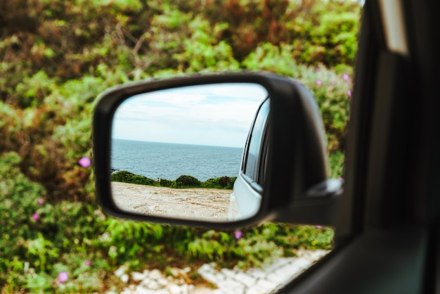 Foto riflessione del mare nel viaggio su strada dello specchietto retrovisore dell'auto