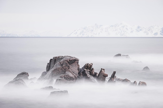 写真 雪の岩と遠くの山に囲まれた海