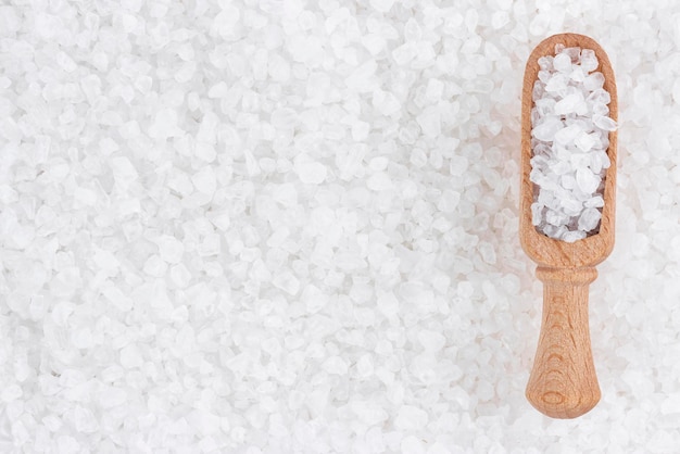 Sea salt background with wooden scoop top view