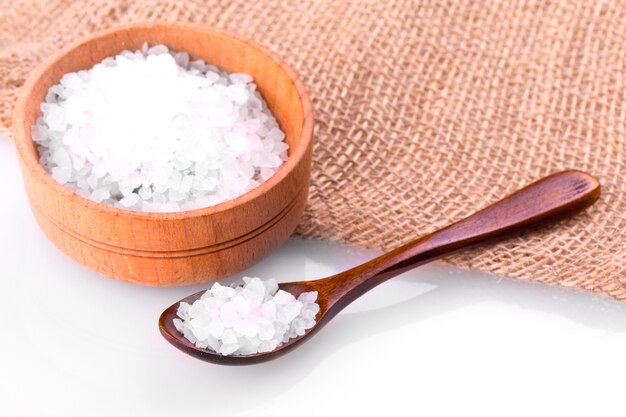 Photo sea salt on cup, spoon and burlap on a white background.