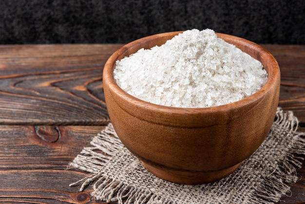 Sea salt on dark wooden background.